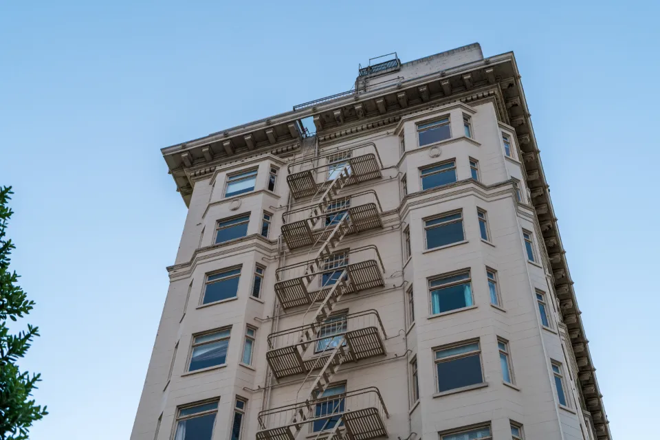 Tall brick apartment building with fire escapes
