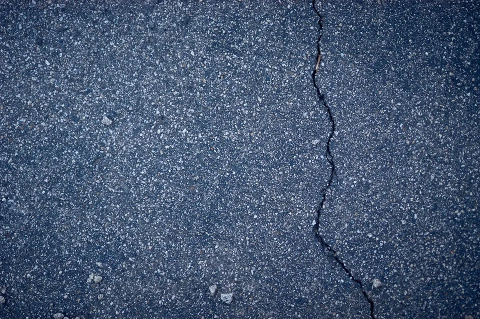 Close-up of a crack running through an asphalt driveway