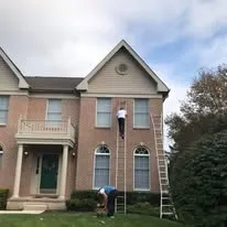 Crew on ladders working on the exterior of a two-story brick house
