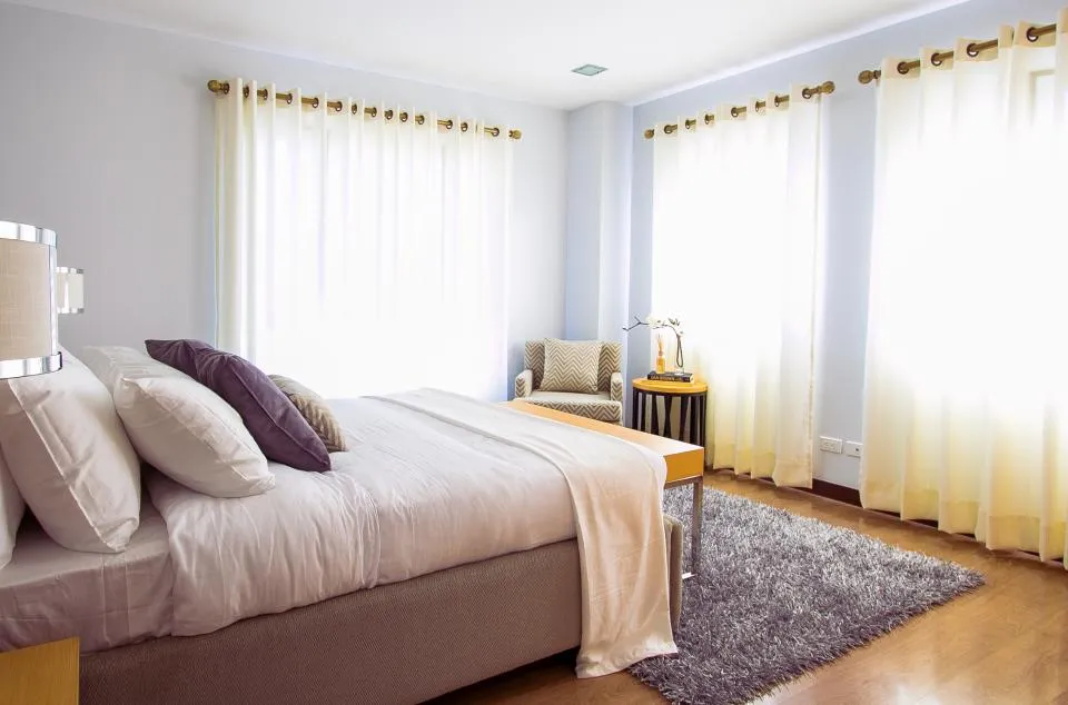 Bright bedroom with a made bed and sheer curtains