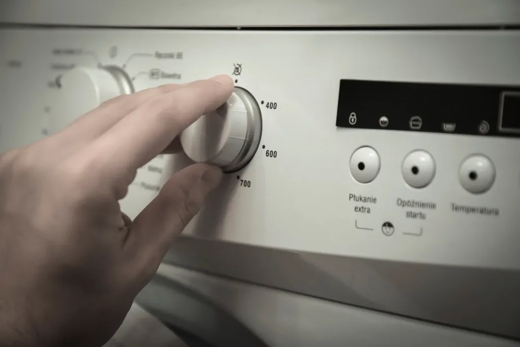 Hand turning the cycle dial on a clothes dryer