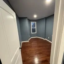 Small room with grey walls, recessed lights and a new hardwood floor