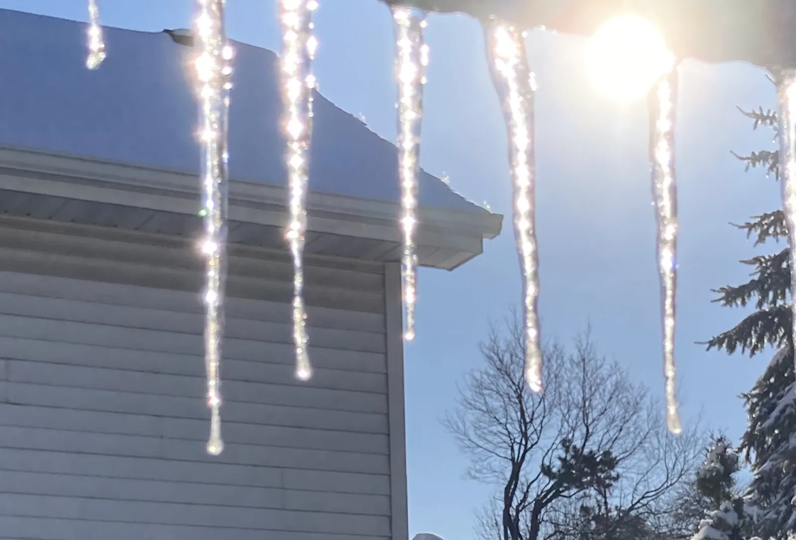 Icicles hanging from a house roof edge and gutter