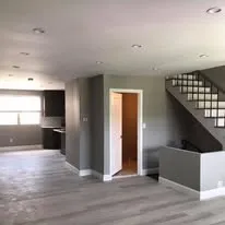 Open-plan renovation with grey walls, new flooring and a staircase