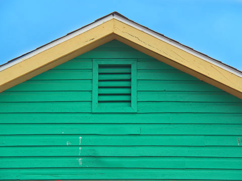 Freshly painted green house siding under a clear blue sky
