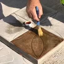 Crew member brushing sealer onto a stamped concrete paver