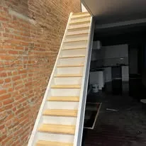 New wooden staircase along an exposed brick wall